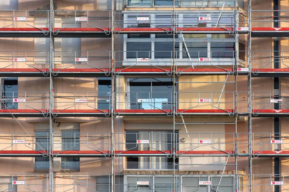 Échafaudage à garde-corps rouges monté sur toute la façade d'un immeuble